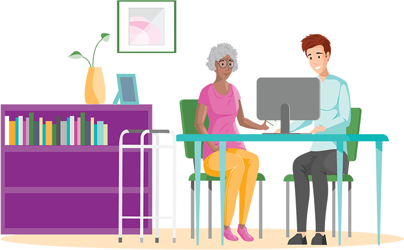 Elderly woman and caregiver sitting at a table working on a computer with her walker nearby and a bookshelf with a picture on the wall